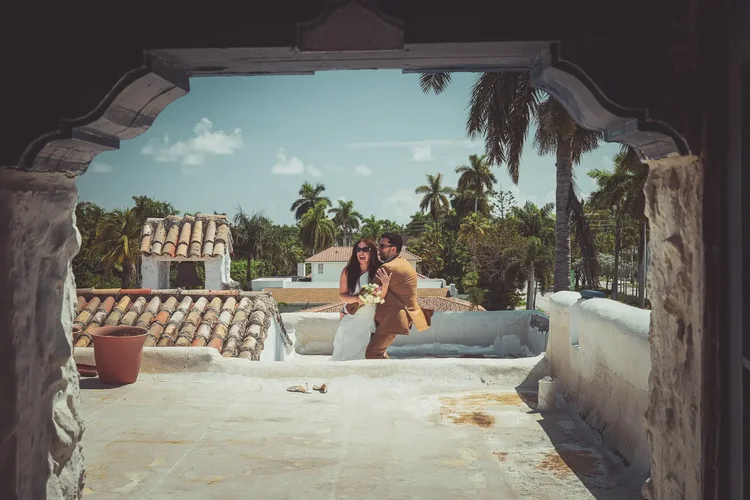 The couple framed through a stucco arch on the Young Mansion rooftop