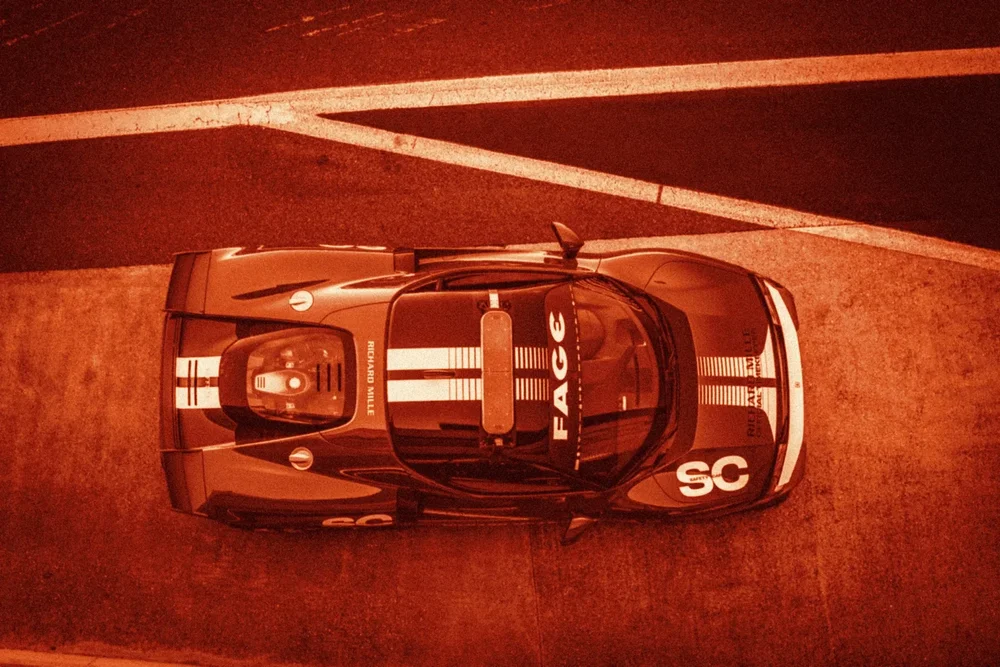 A striped race car seen from directly above, toned red and orange