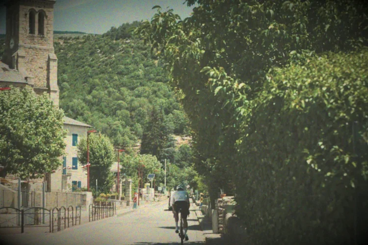 James riding through a village under a church tower