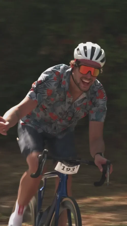 A rider in a floral jersey grinning on the lanes