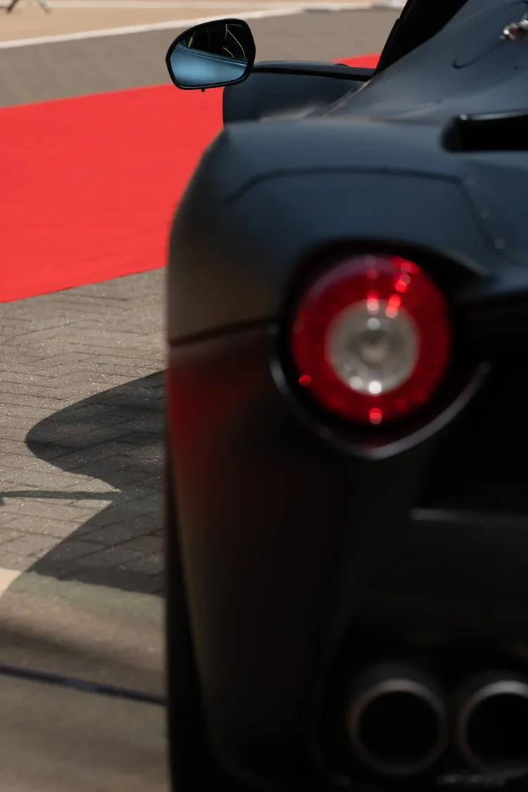 A round tail light and twin exhausts on a matte black car