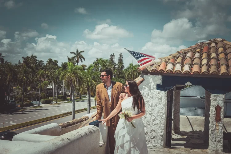 Newlyweds on the rooftop terrace above Hollywood Boulevard under terracotta tiles and palm trees