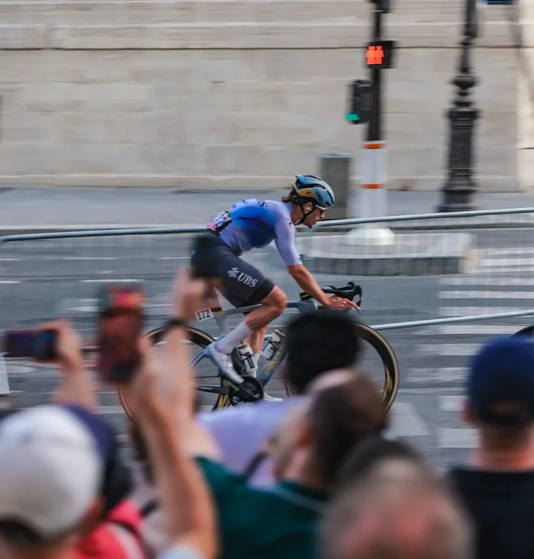 Panning shot of a rider racing past spectators filming on their phones in Paris, Tour de France 2026