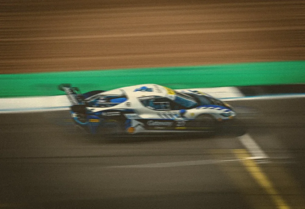 A race car smeared into horizontal streaks of colour along the pit straight