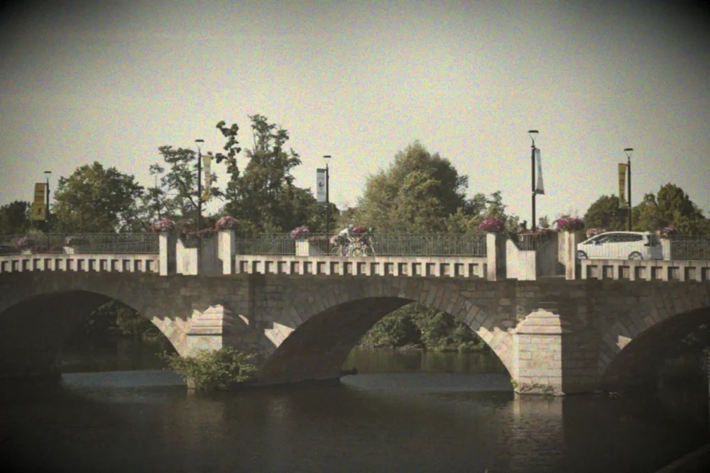 A stone bridge over a river in a French village, soft pastel Autochrome colour