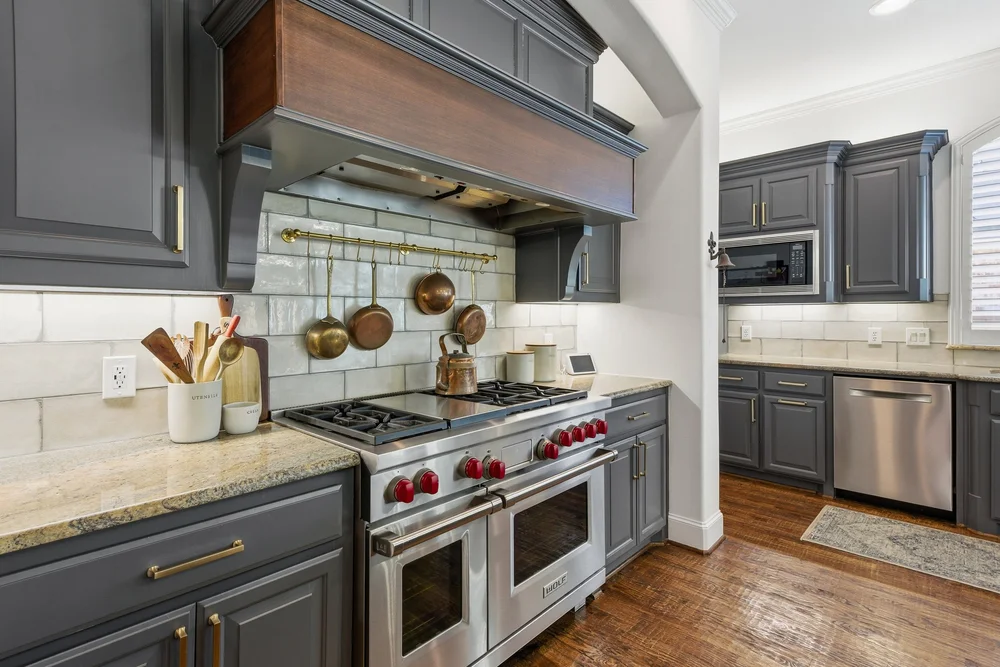 Kitchen with a gas range, custom hood and built-in appliances