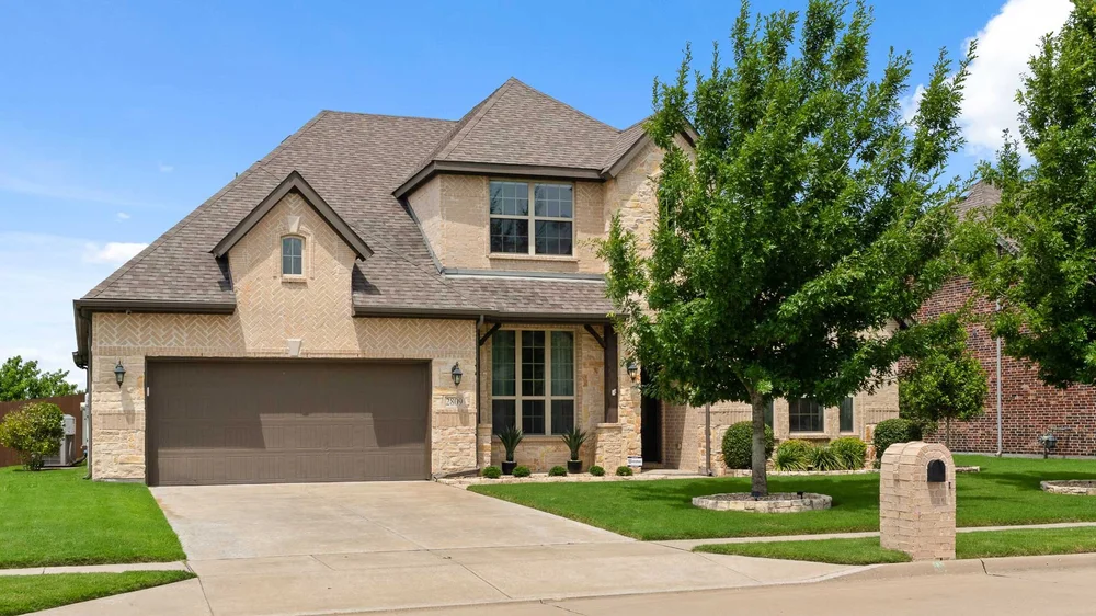 Two-story brick home with mature trees and a landscaped front yard