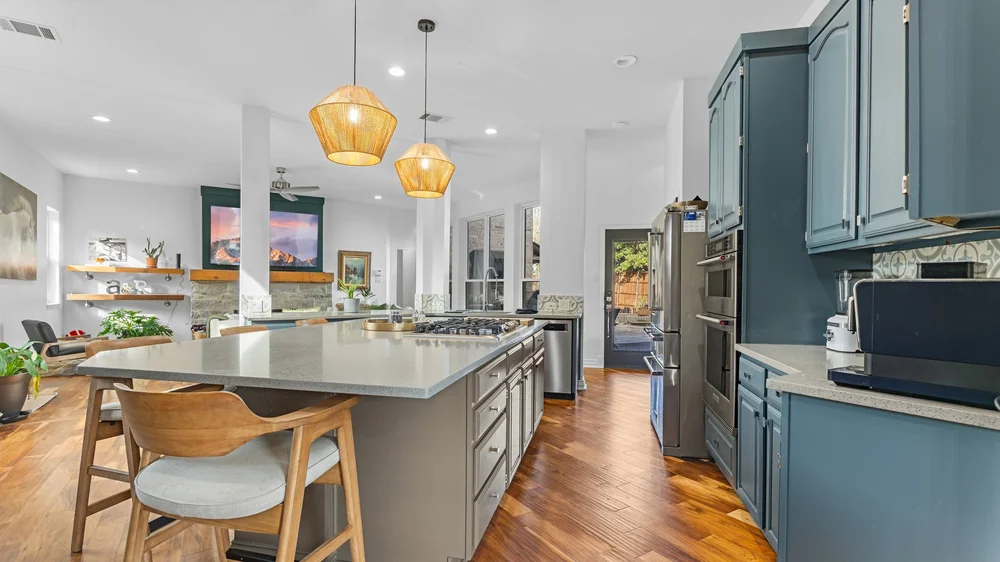 Blue kitchen cabinets and a large island opening to a bright living area
