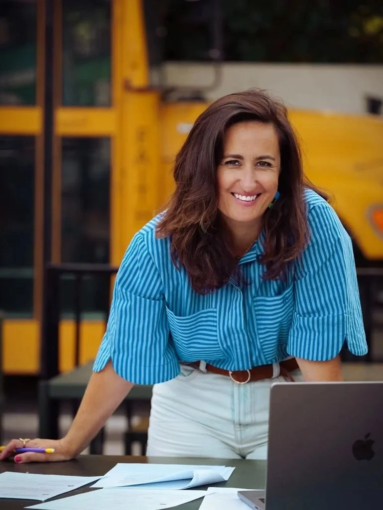 Portrait de Christelle Sérou, souriante, penchée sur des textes à côté de son ordinateur
