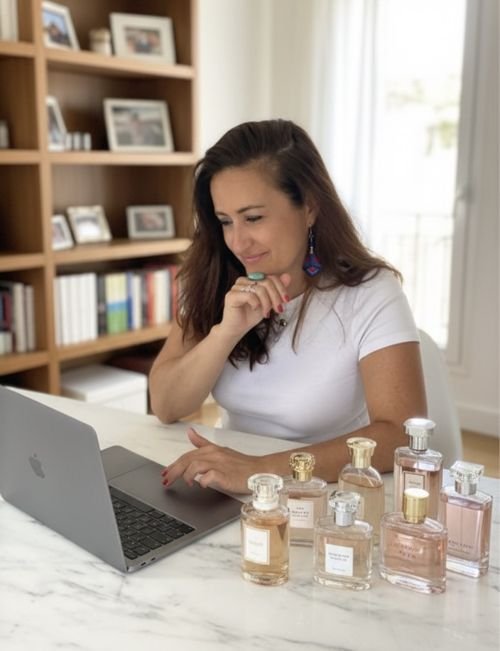 Christelle Sérou au travail sur son ordinateur, entourée de flacons de parfum