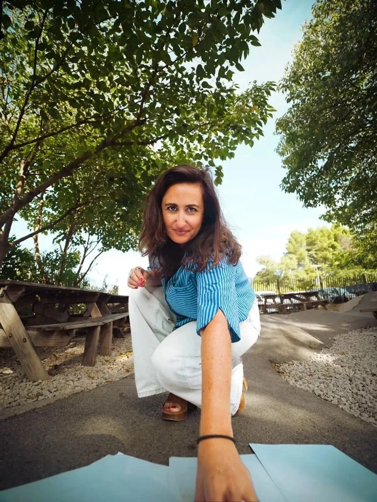 Christelle Sérou accroupie, tendant la main vers des feuilles posées au sol