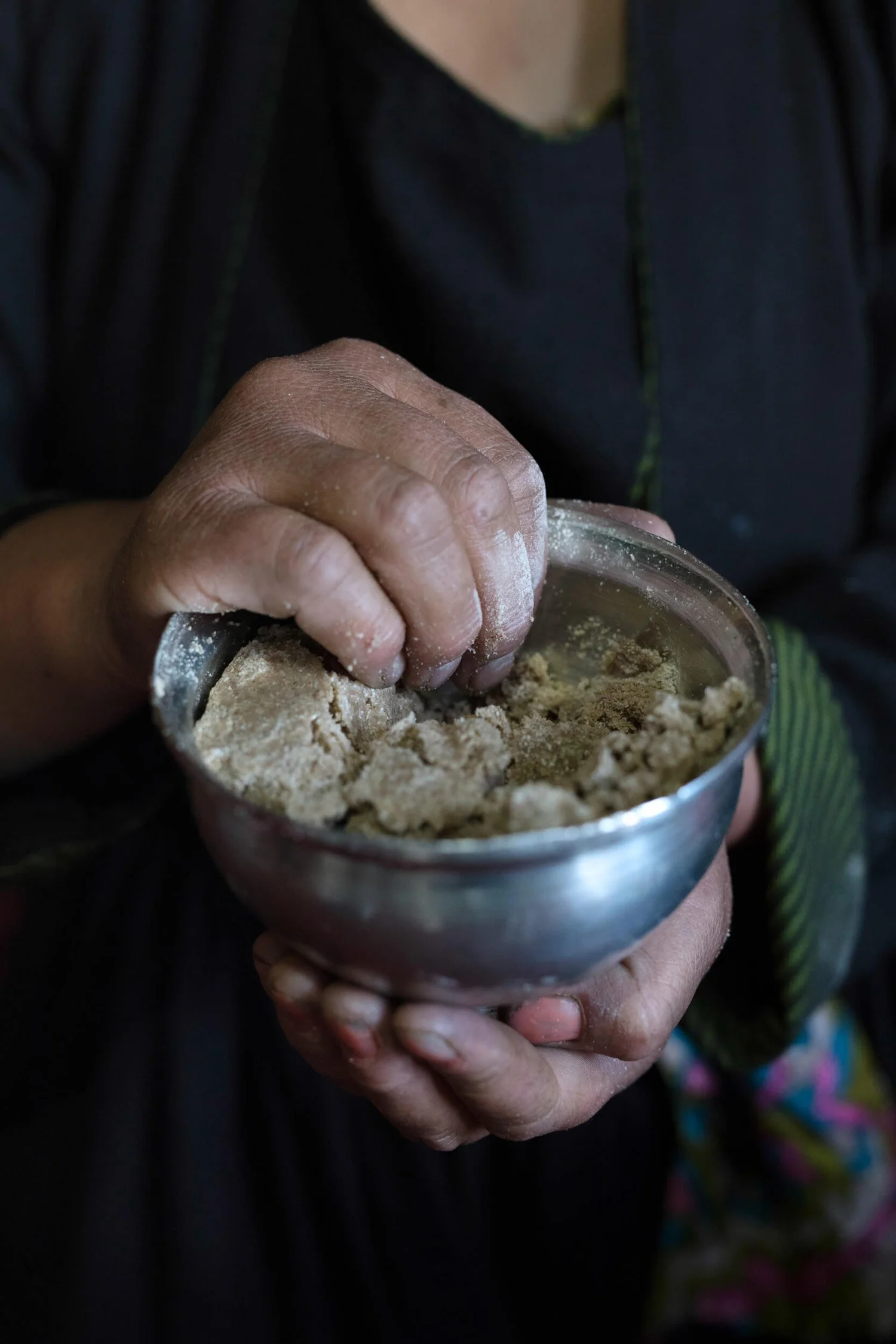 Hands kneading tsampa flour into kholak in a metal bowl