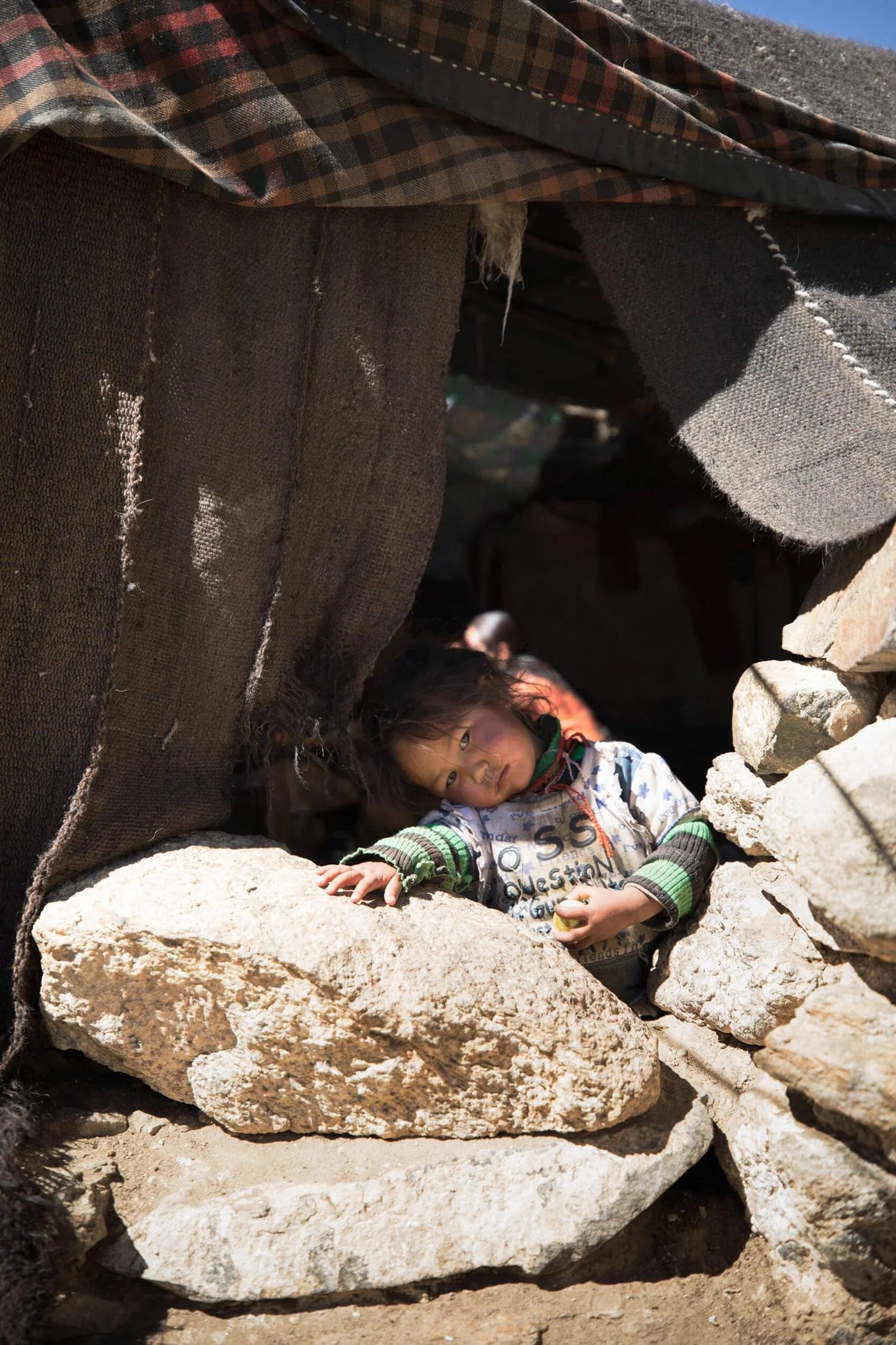 A young Chang-pa infant peering out from a stone shelter