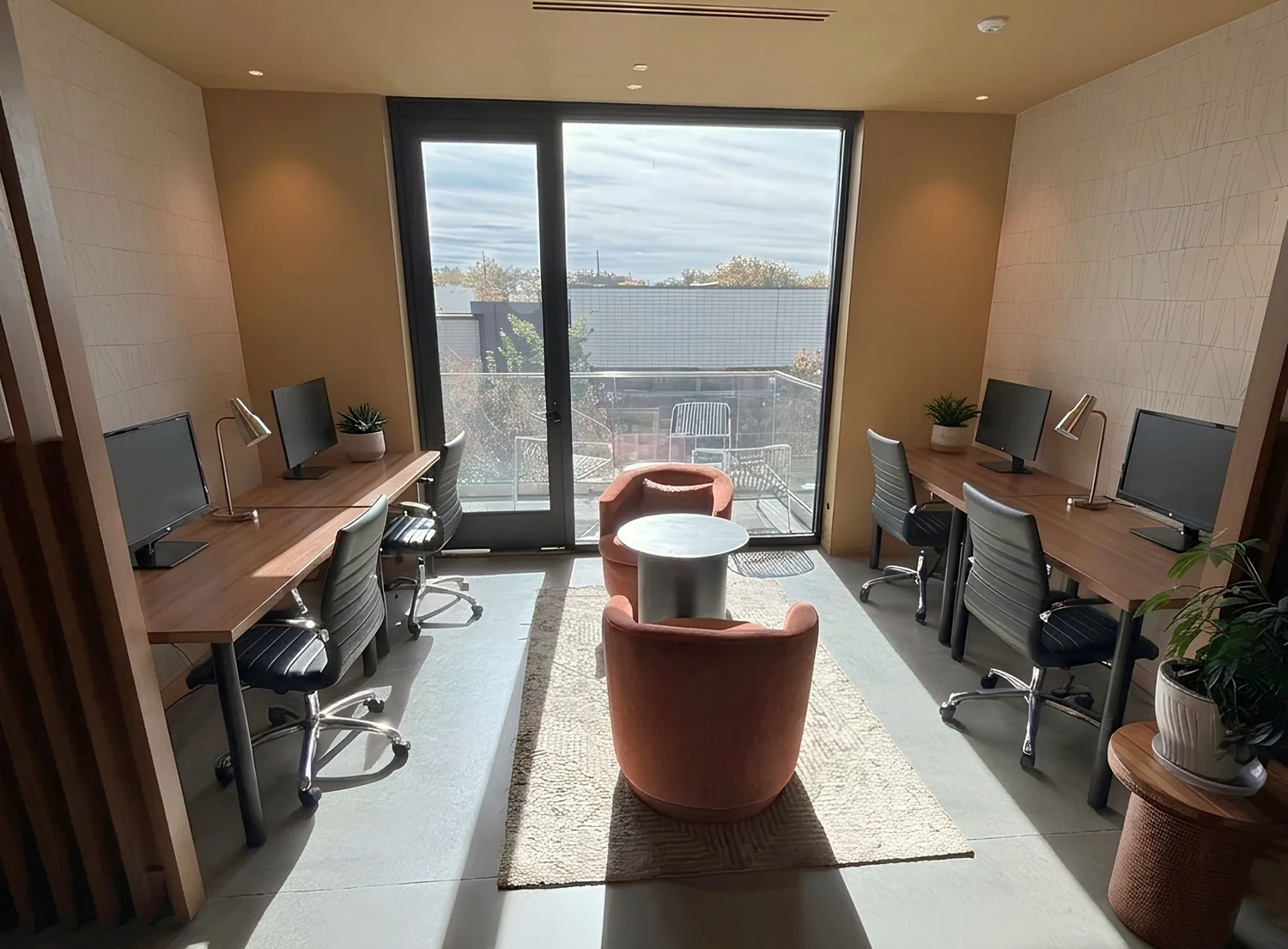 The Sunshine Nook at Tarra: four dedicated desks with monitors and lamps on either side of a floor-to-ceiling window looking out to the patio