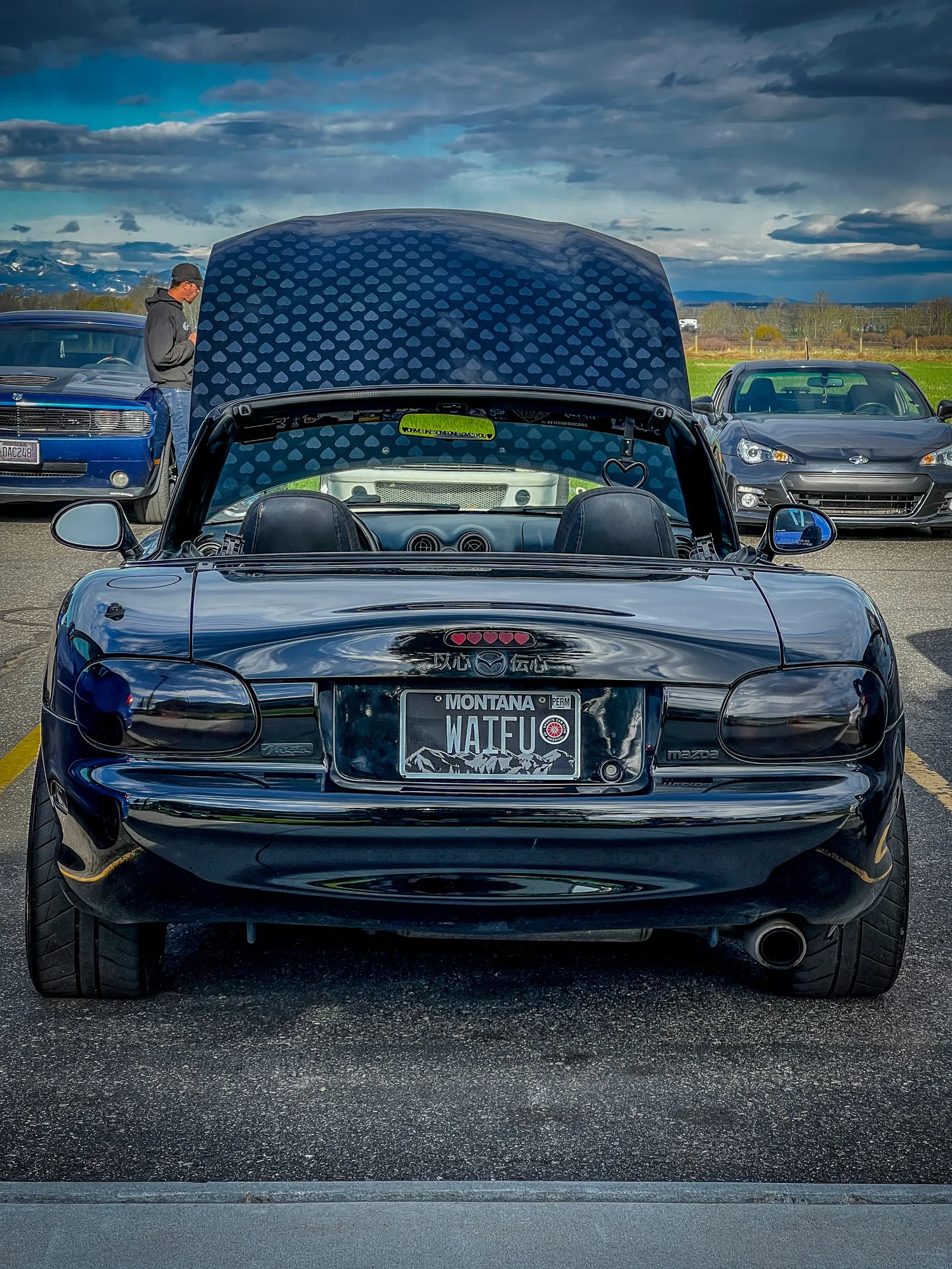 The Love Miata: all-black 1999 Mazda Miata with color-shift hearts on the hood and WAIFU plates