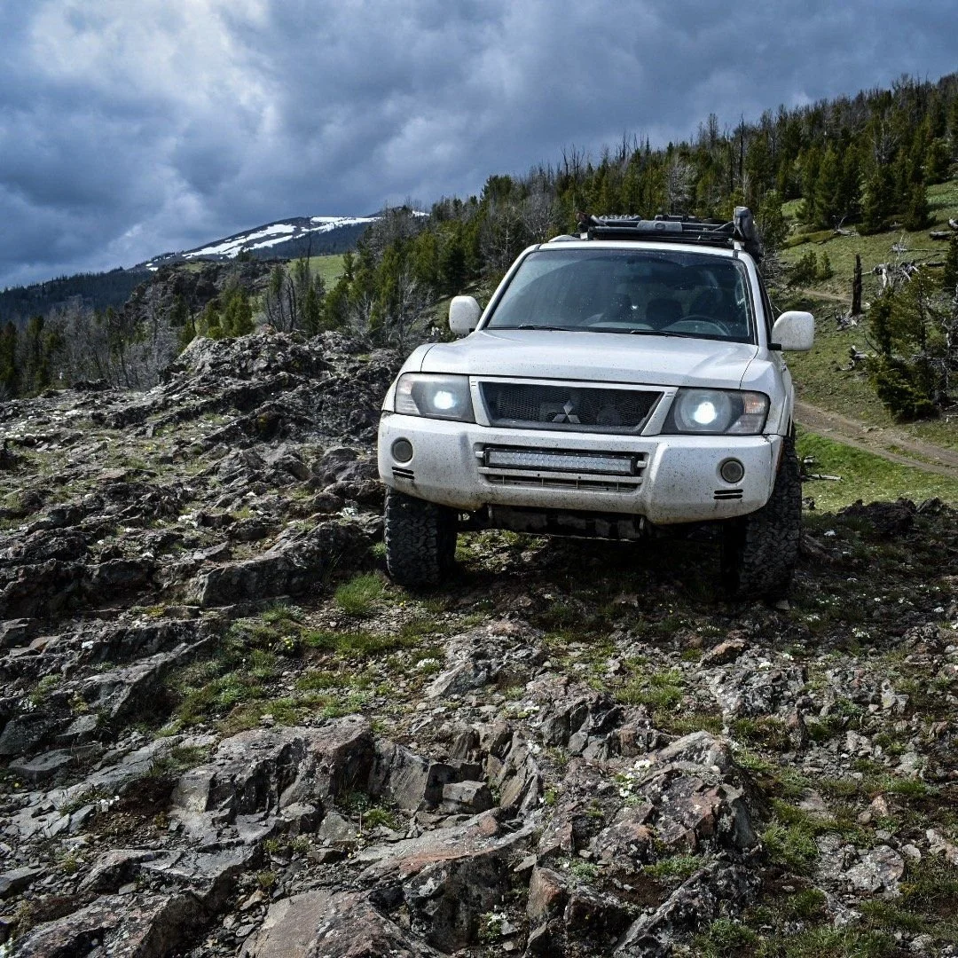 White Mitsubishi Montero climbing over rocks on a high ridge in the Elkhorn Mountains near Boulder, Montana