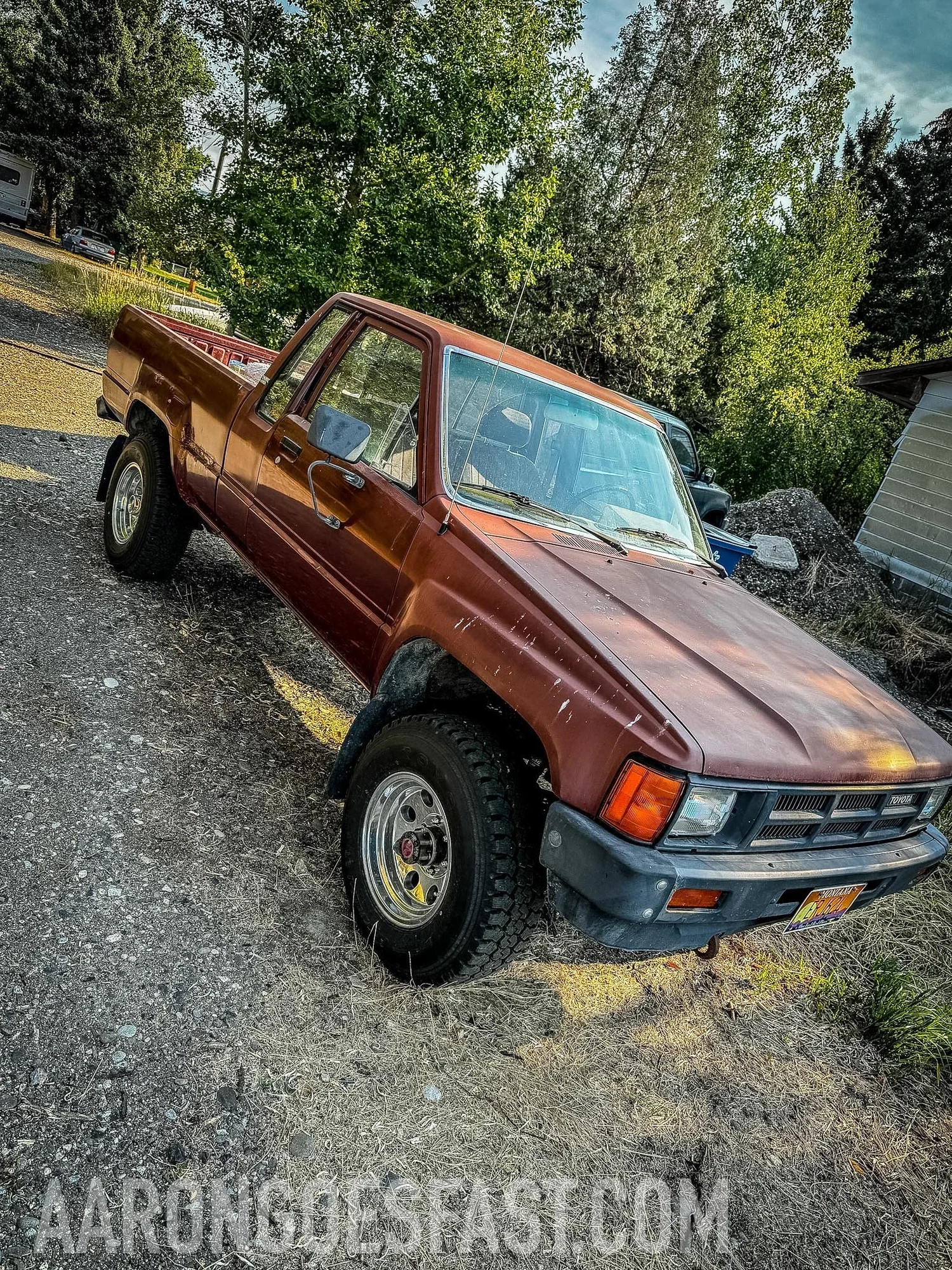 Red Toyota pickup on a gravel driveway