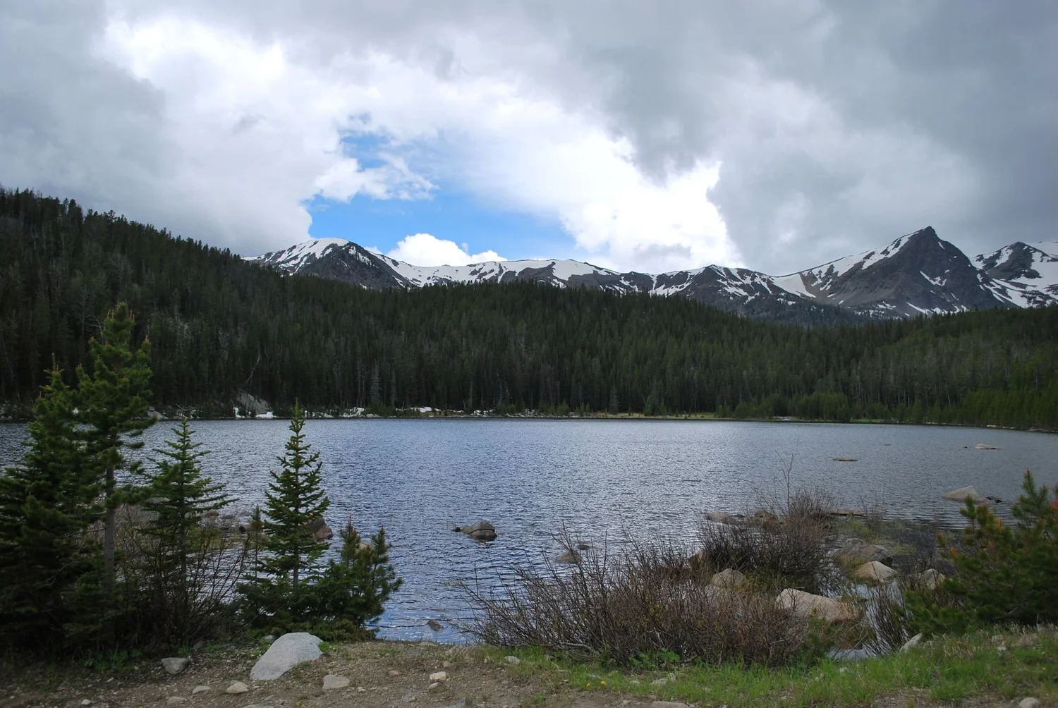 Wide mountain lake below a ridge of snow-streaked peaks under scattered clouds on the North Meadow Creek Twin Lakes trail in the Tobacco Root Mountains, Montana