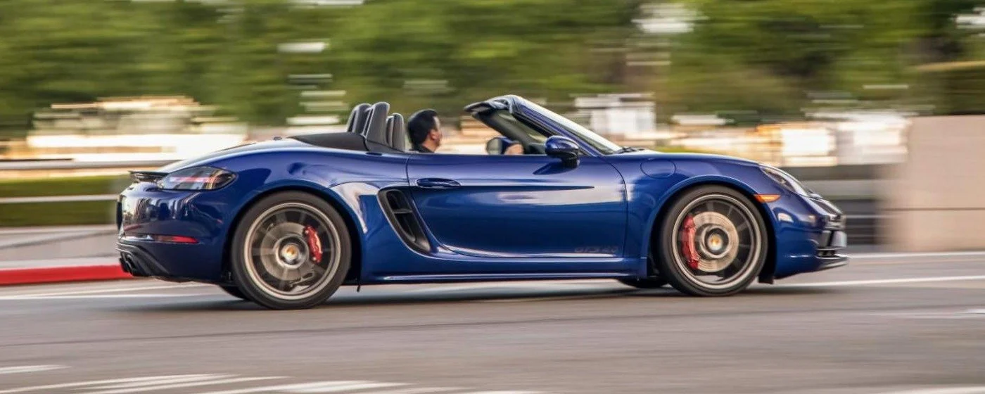 Blue Porsche 718 Boxster GTS 4.0 driving with its top down