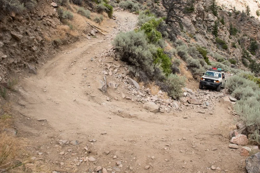 Tight dirt switchback turn with a 4x4 coming around the corner above