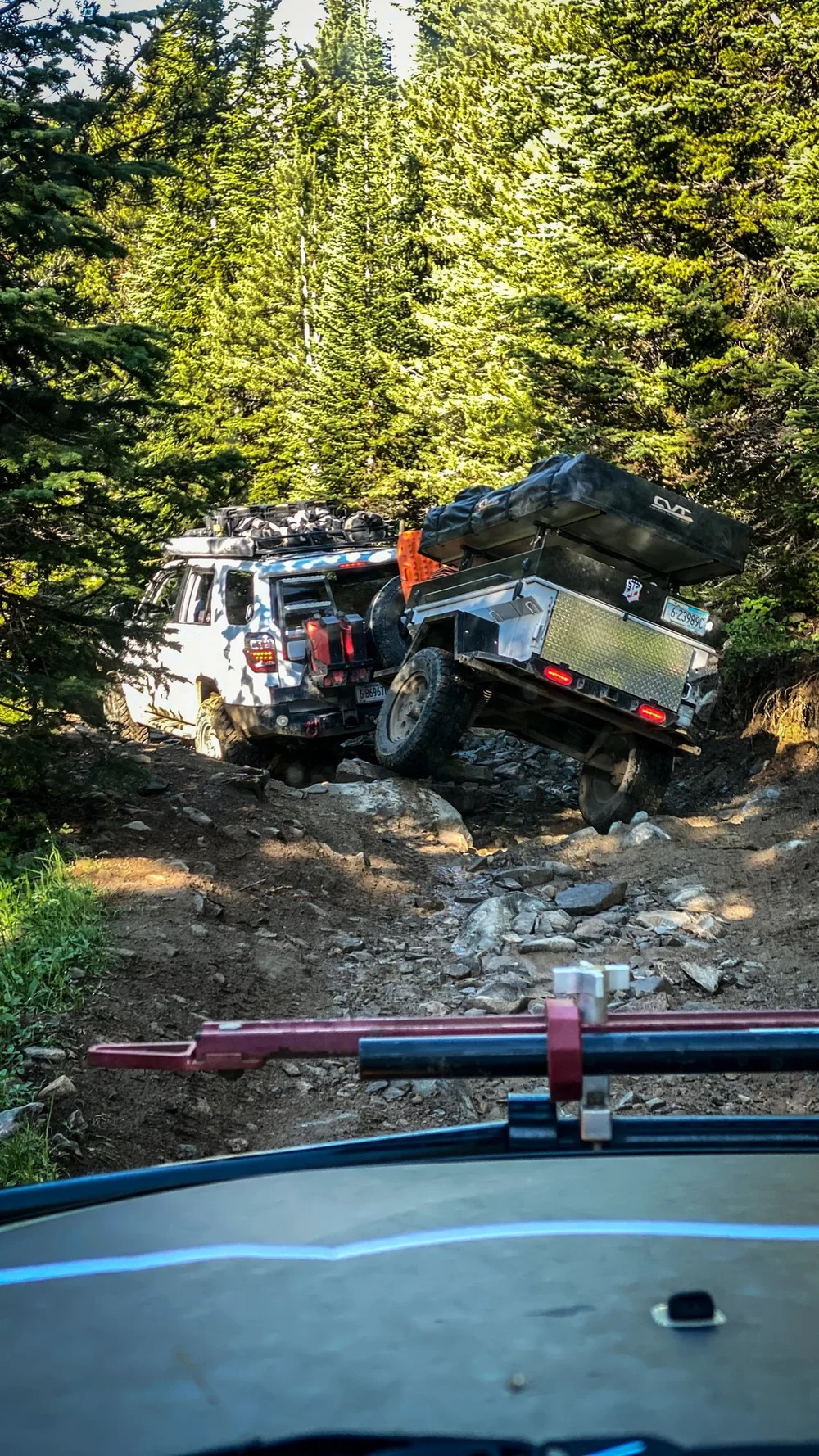 View over the hood of a rig ahead climbing a rocky, rutted section