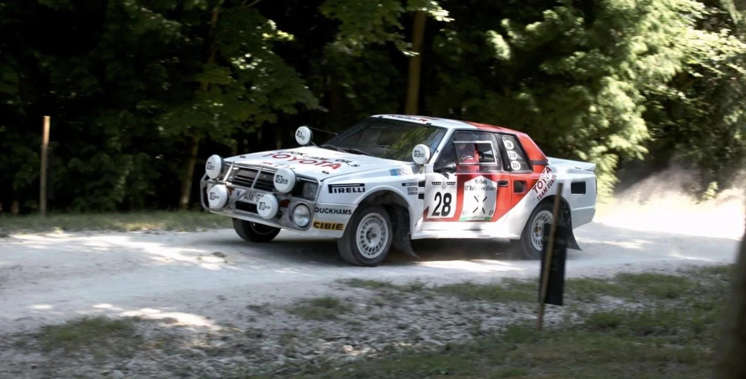 White and red Toyota Celica Twin-Cam Group B rally car on a gravel stage at Goodwood