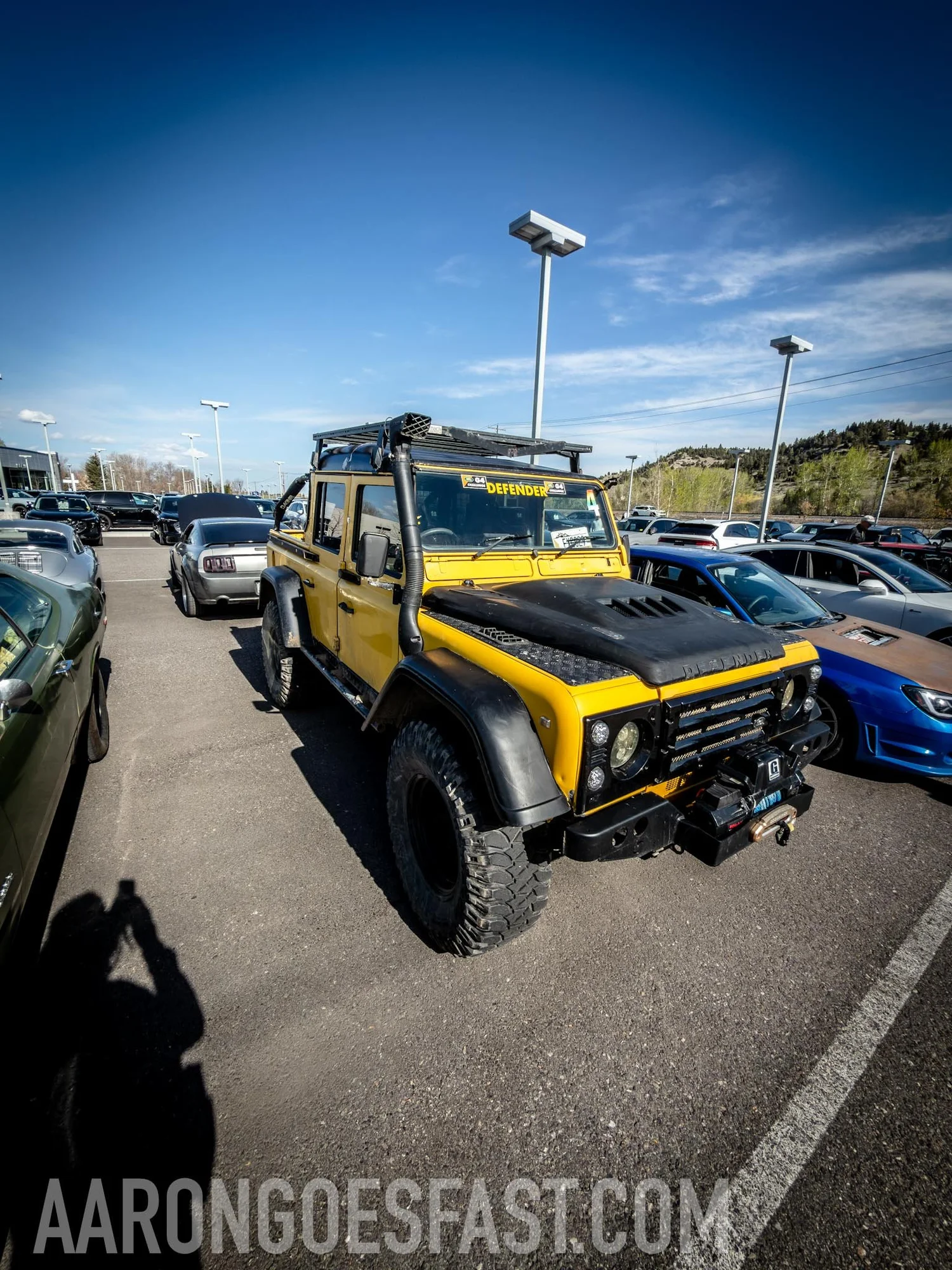 Yellow Land Rover Defender with snorkel, roof rack and winch