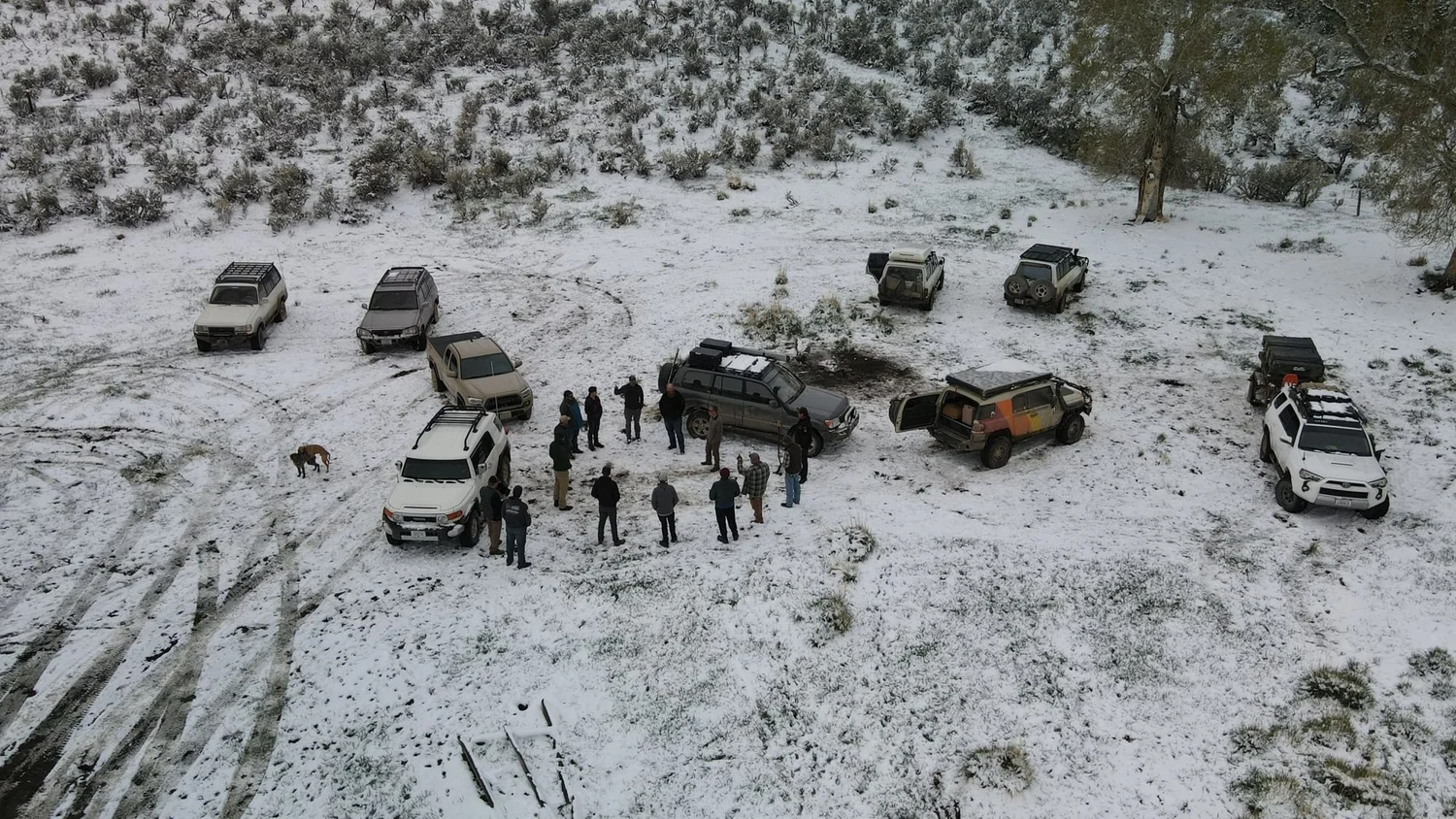 Drone view of a group of trucks and people gathered in a snowy clearing on a 406 Cruisers run in the upper Ruby River country, Montana