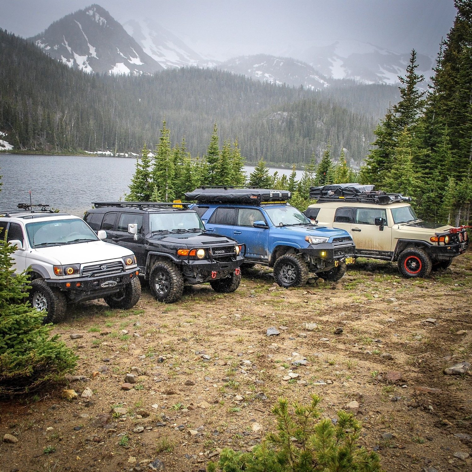 Toyotas parked on a lakeshore with storm clouds over snowy peaks on the North Meadow Creek Twin Lakes trail in the Tobacco Root Mountains, Montana