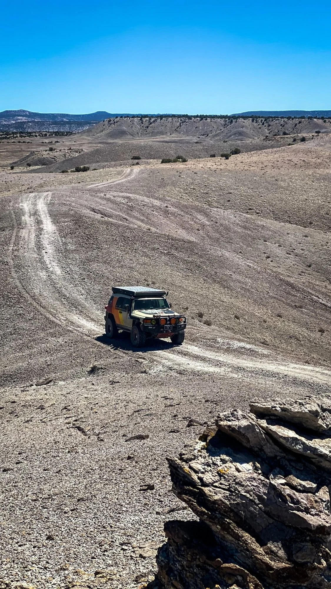 FJ Cruiser on a gray desert two-track seen from a rocky point above on a spring road trip through Utah