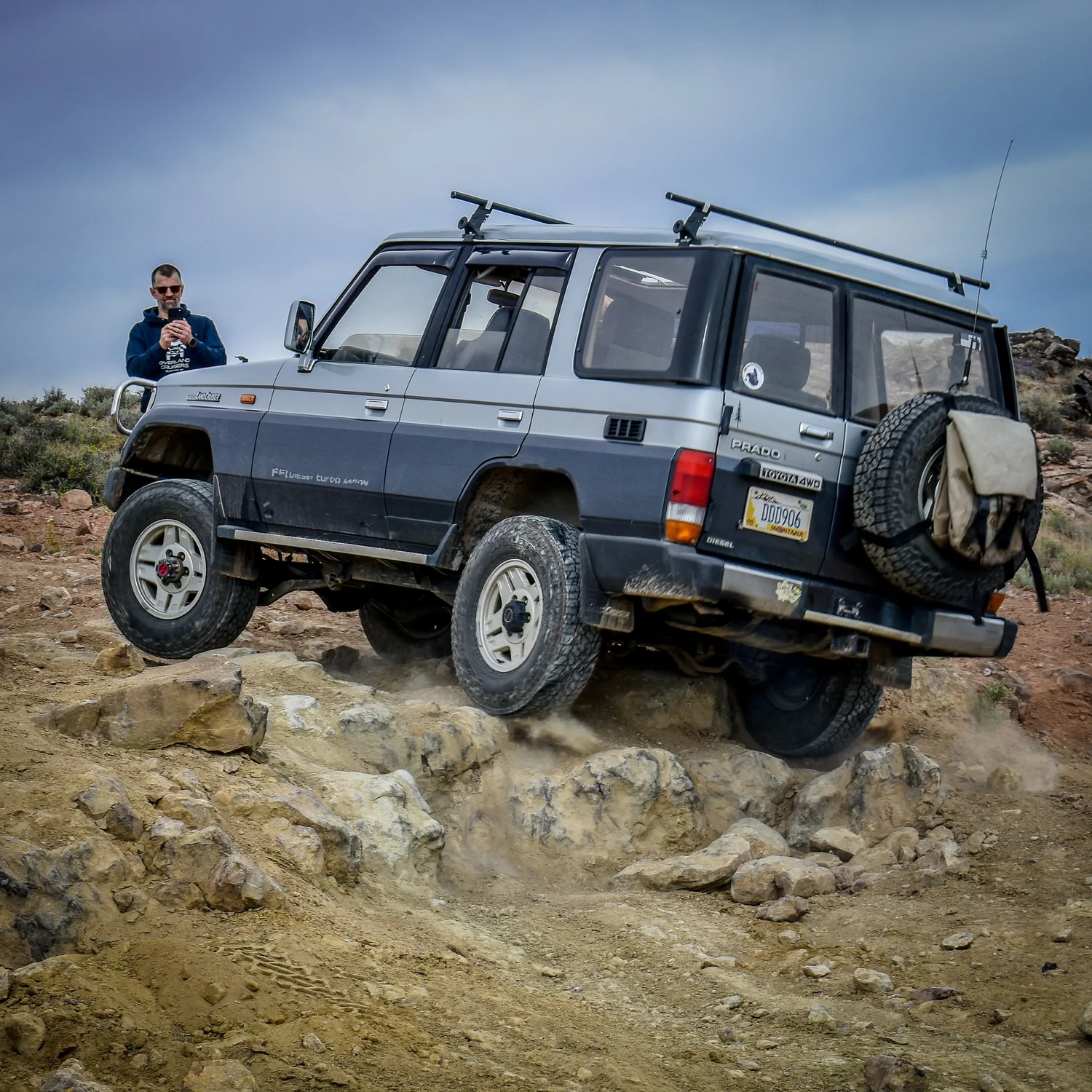 Gray two-tone 70 Series Toyota Land Cruiser wagon crawling over a rock ledge on the 3D Trail at Cruise Moab