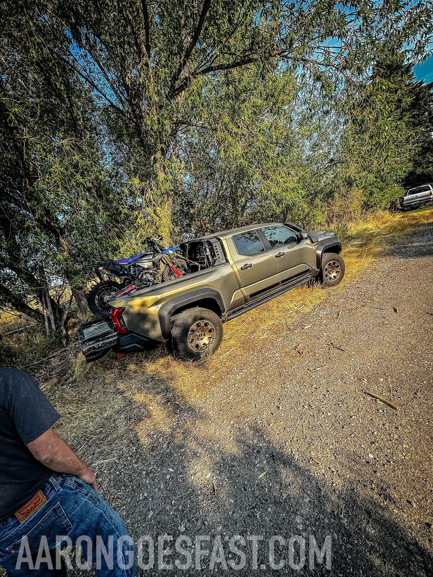 Tacoma Trailhunter parked under trees with a dirt bike in the bed