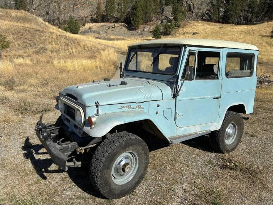 Light blue 1967 Toyota FJ40 Land Cruiser hardtop with a white roof parked in a dry Montana field