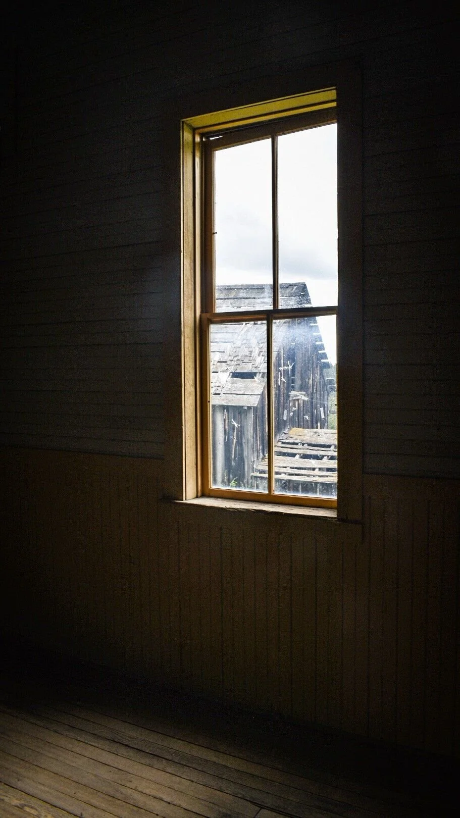 Single bright window in a dark wooden room inside an old Elkhorn building in the Elkhorn ghost town near Boulder, Montana