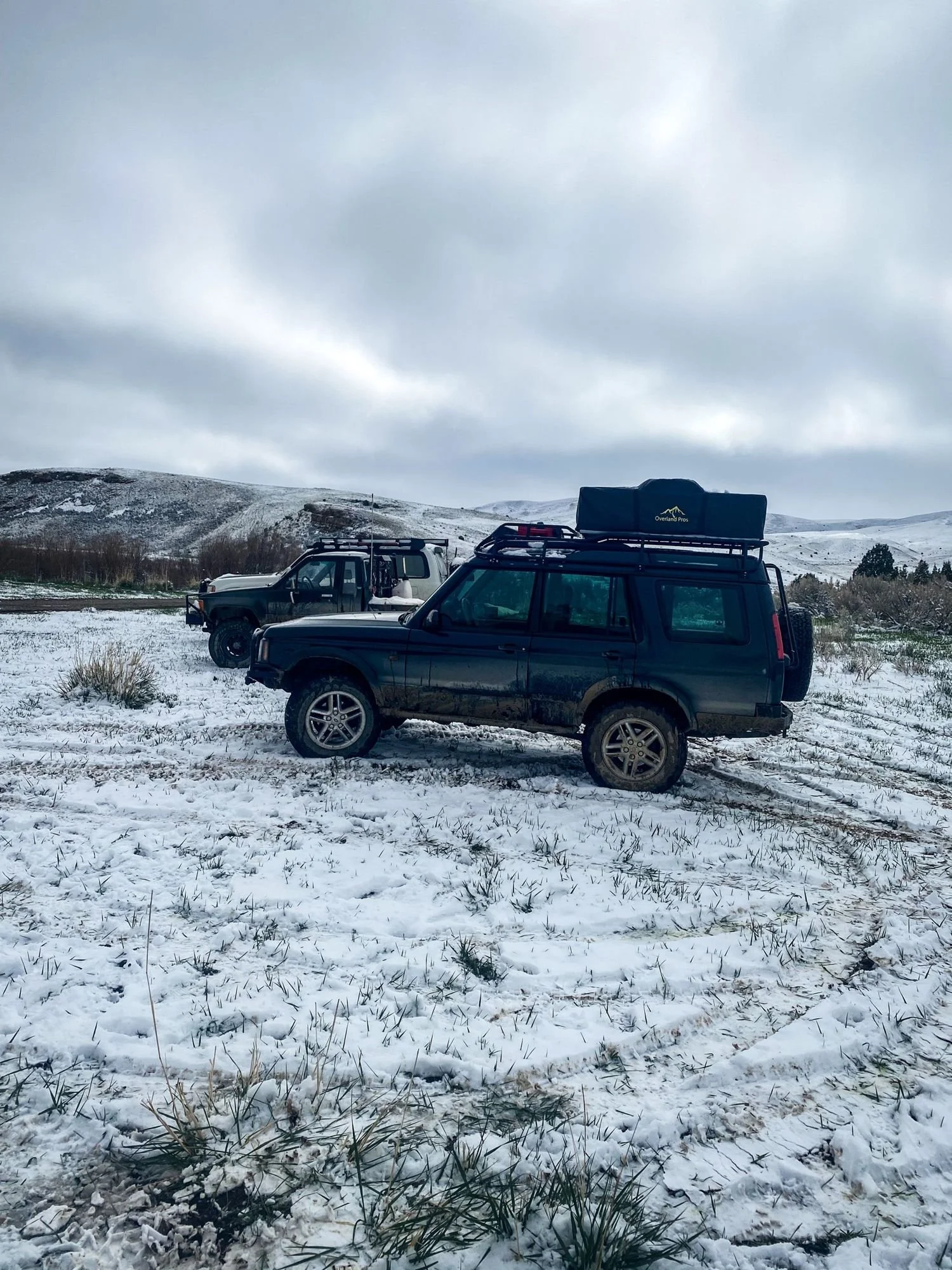 Dark green Land Rover Discovery with a roof rack parked in a snowy field on a 406 Cruisers run in the upper Ruby River country, Montana