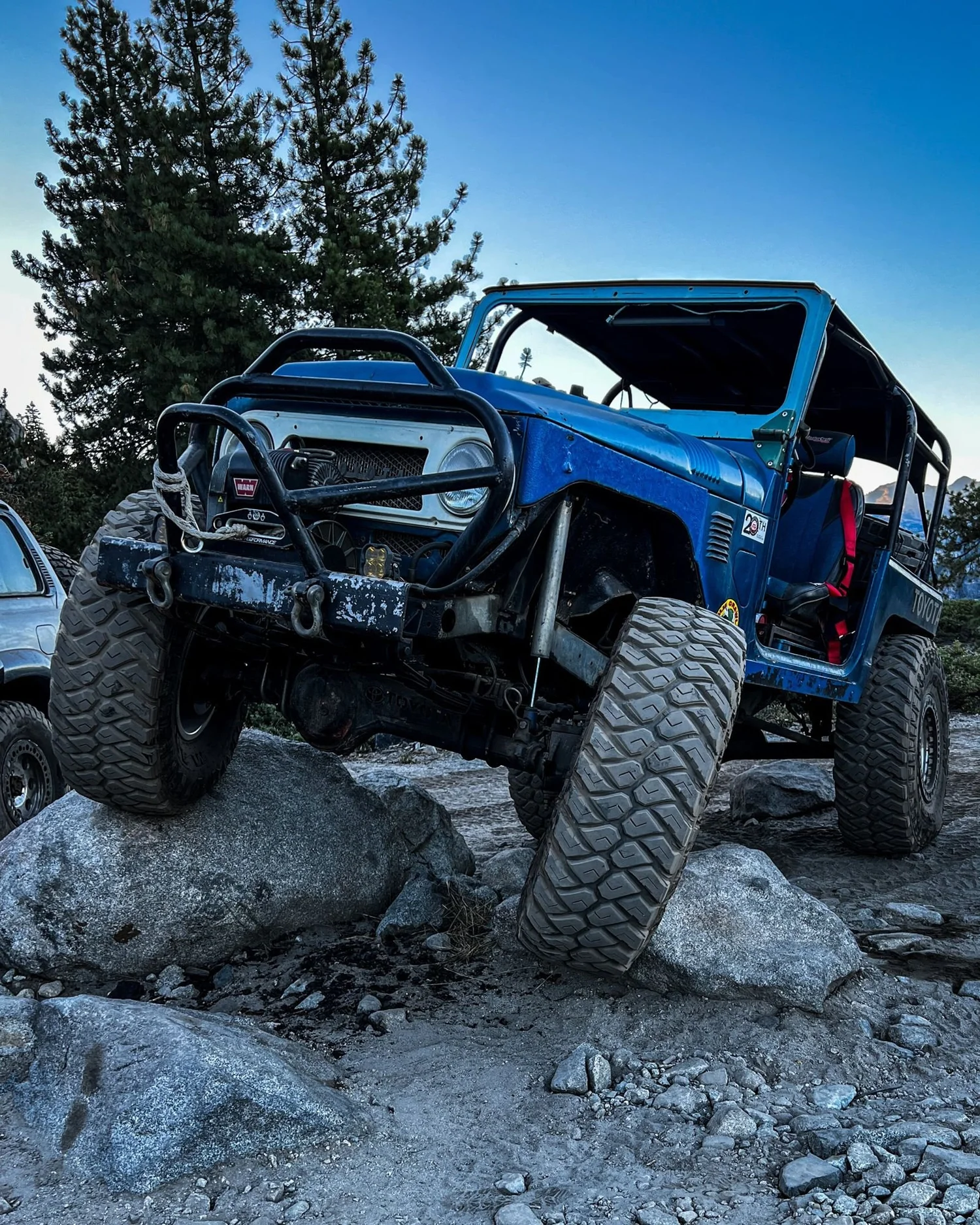 Blue lifted truck with a big front bumper perched on a granite rock on the Rubicon Trail in California during Rubithon 2022