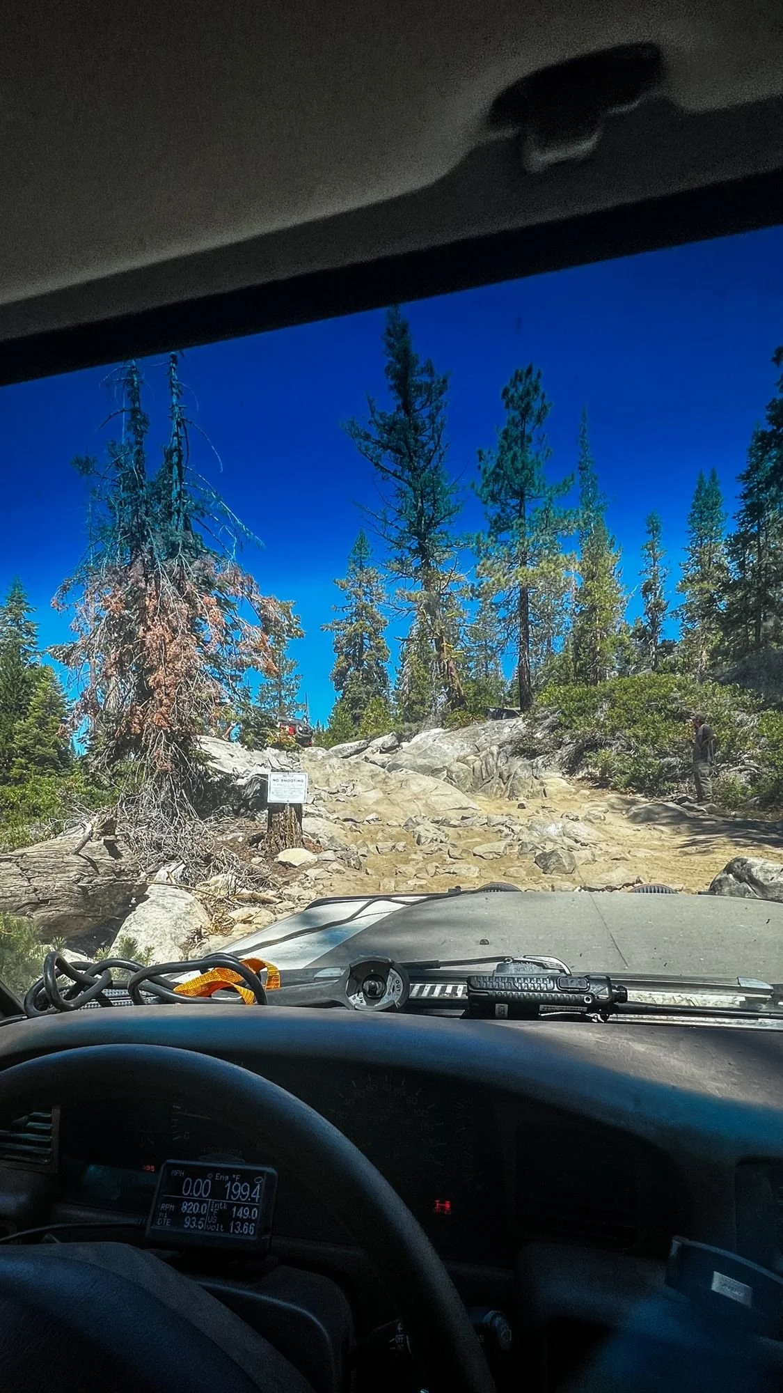 View over a dashboard of a granite trail climbing through pines on the Rubicon Trail in California during Rubithon 2022