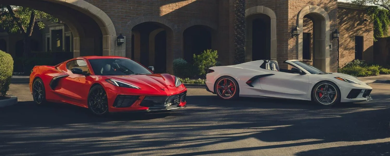 Red Chevrolet Corvette Stingray coupe beside a white Stingray convertible with the roof down