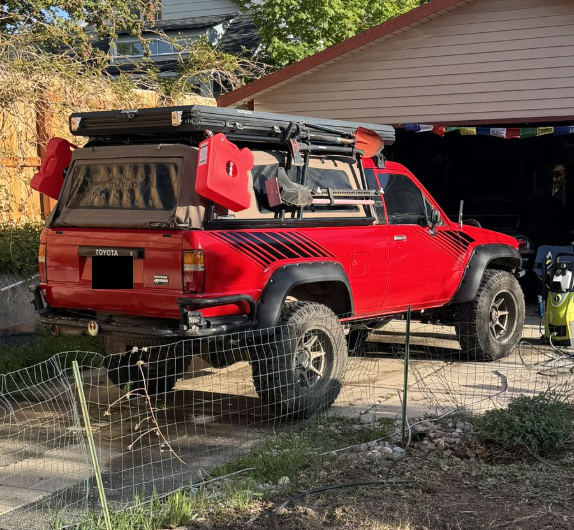Rear view of a red 1989 Toyota 4Runner with a canopy and fuel cans