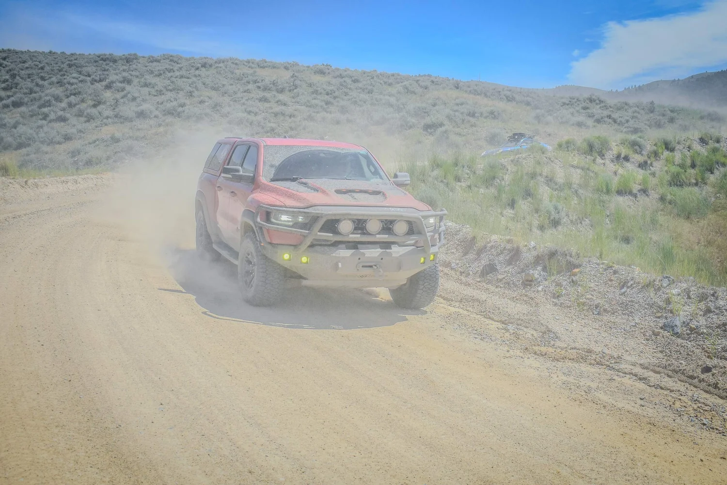 Red Ram off-road truck charging through dust on a Montana dirt road