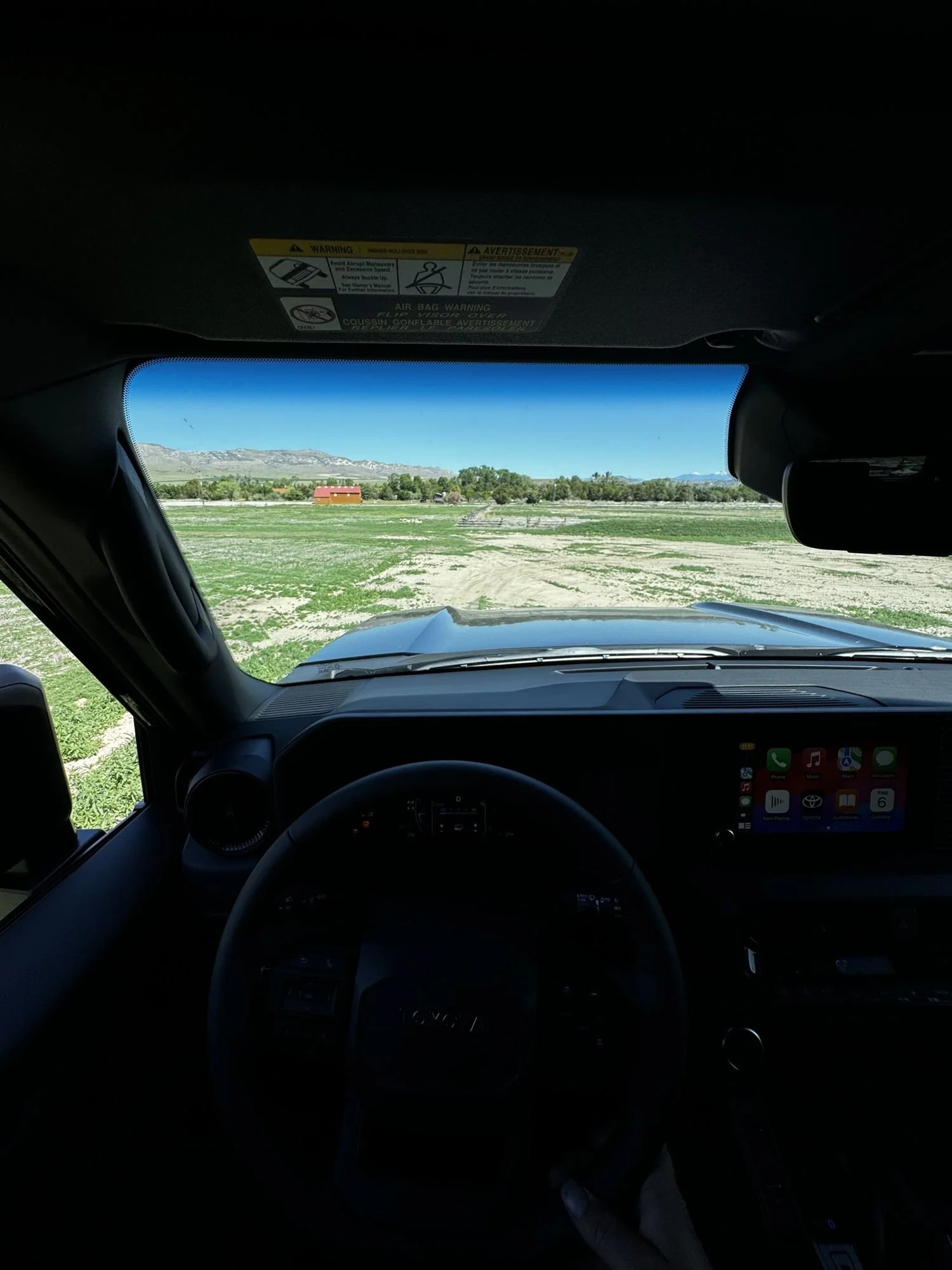 View from the driver’s seat of a 2024 Land Cruiser dashboard and screen looking out over a grassy course at XOverland Ranch near Bozeman, Montana