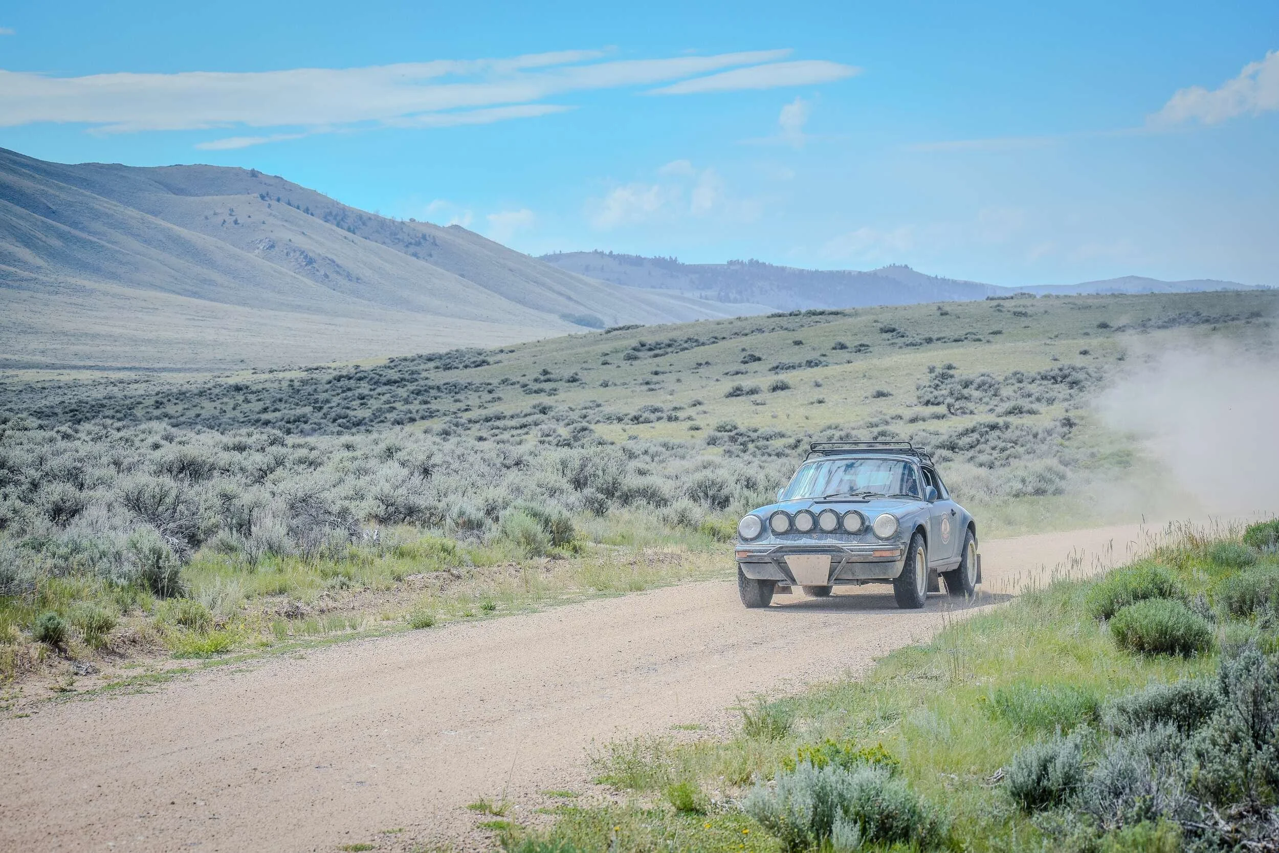 Auxiliary-light-equipped car driving across open Montana country