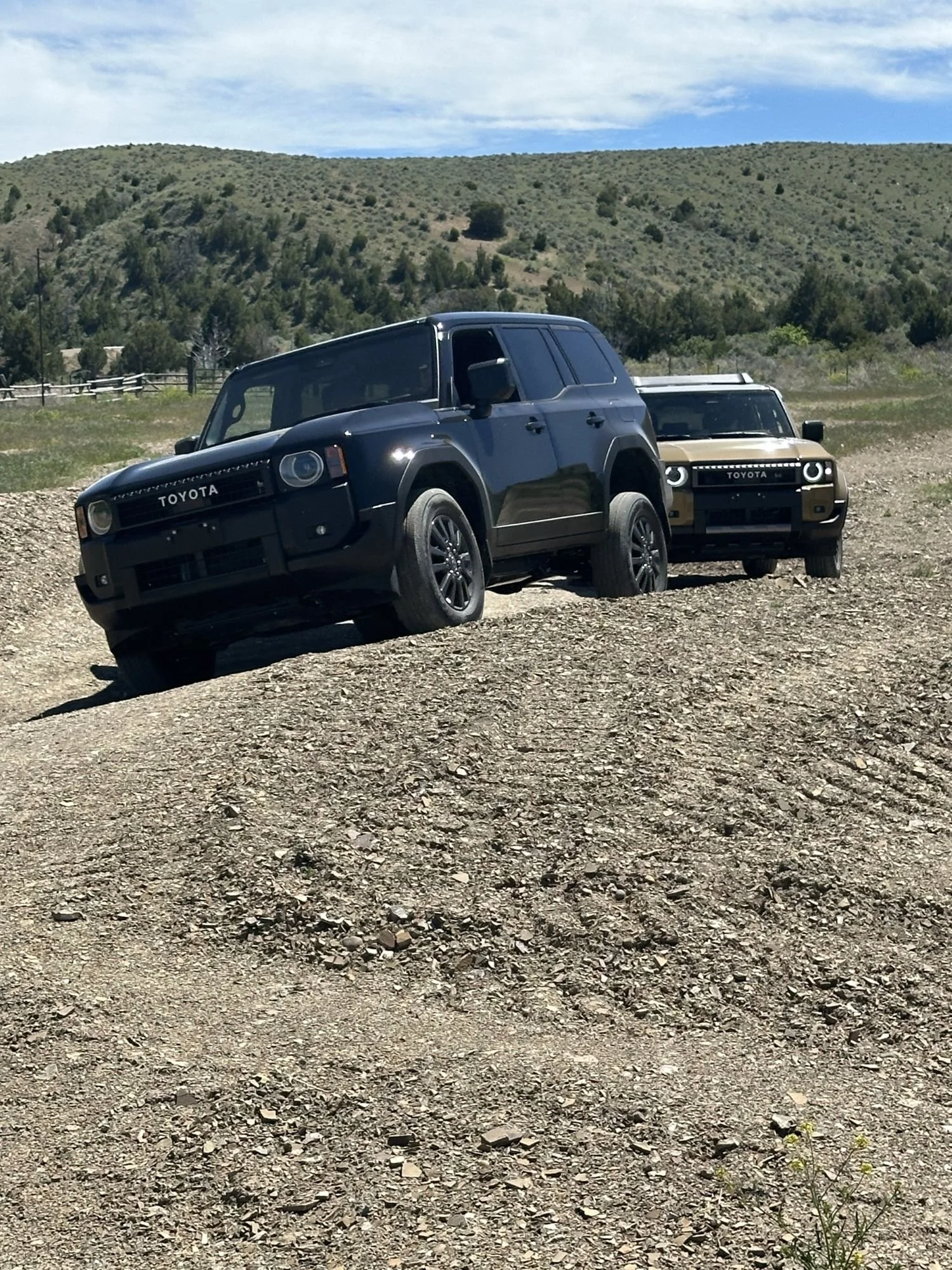 Black Land Cruiser 250 cresting a dirt hump with a tan one behind it at XOverland Ranch near Bozeman, Montana