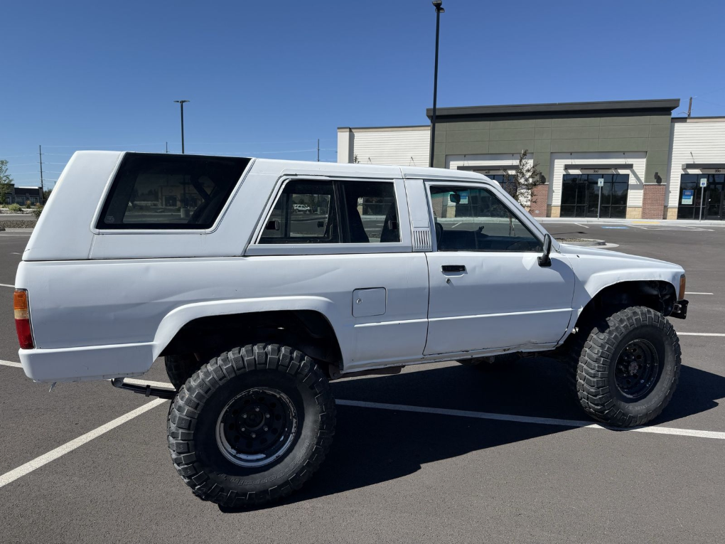 Side profile of a white 1985 Toyota 4Runner on large mud tires