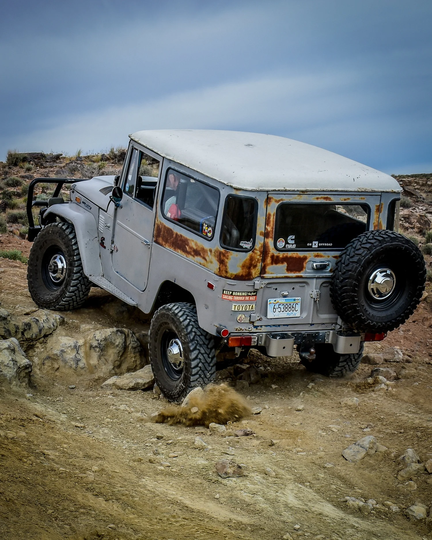 Gray Toyota FJ40 Land Cruiser with a rear spare tire climbing rocks on the 3D Trail at Cruise Moab