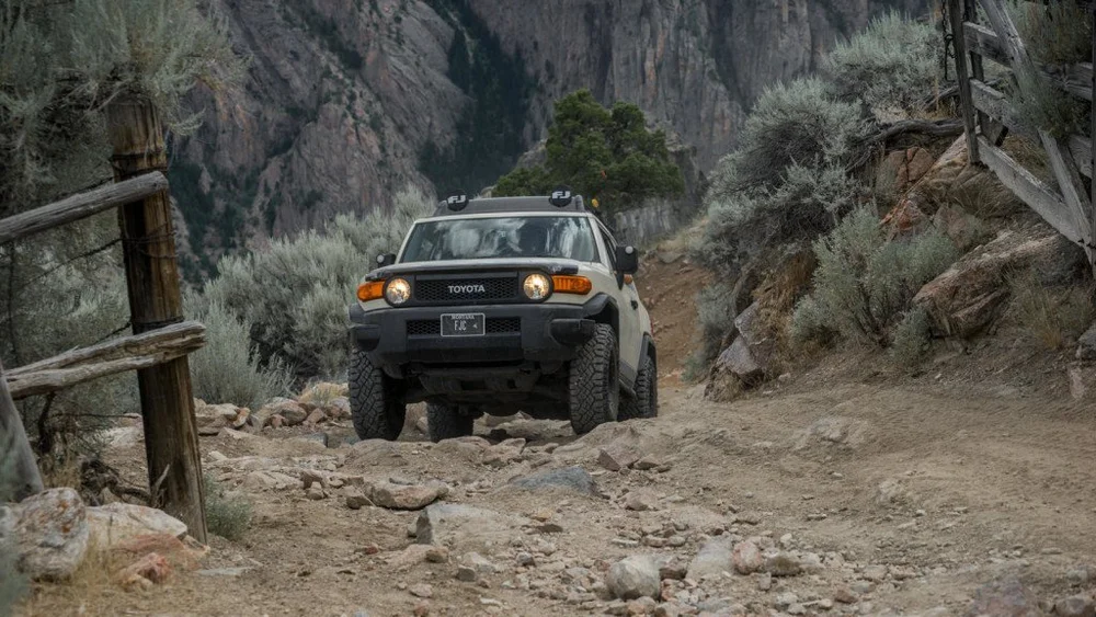 Toyota FJ Cruiser climbing a rocky switchback past old fence posts