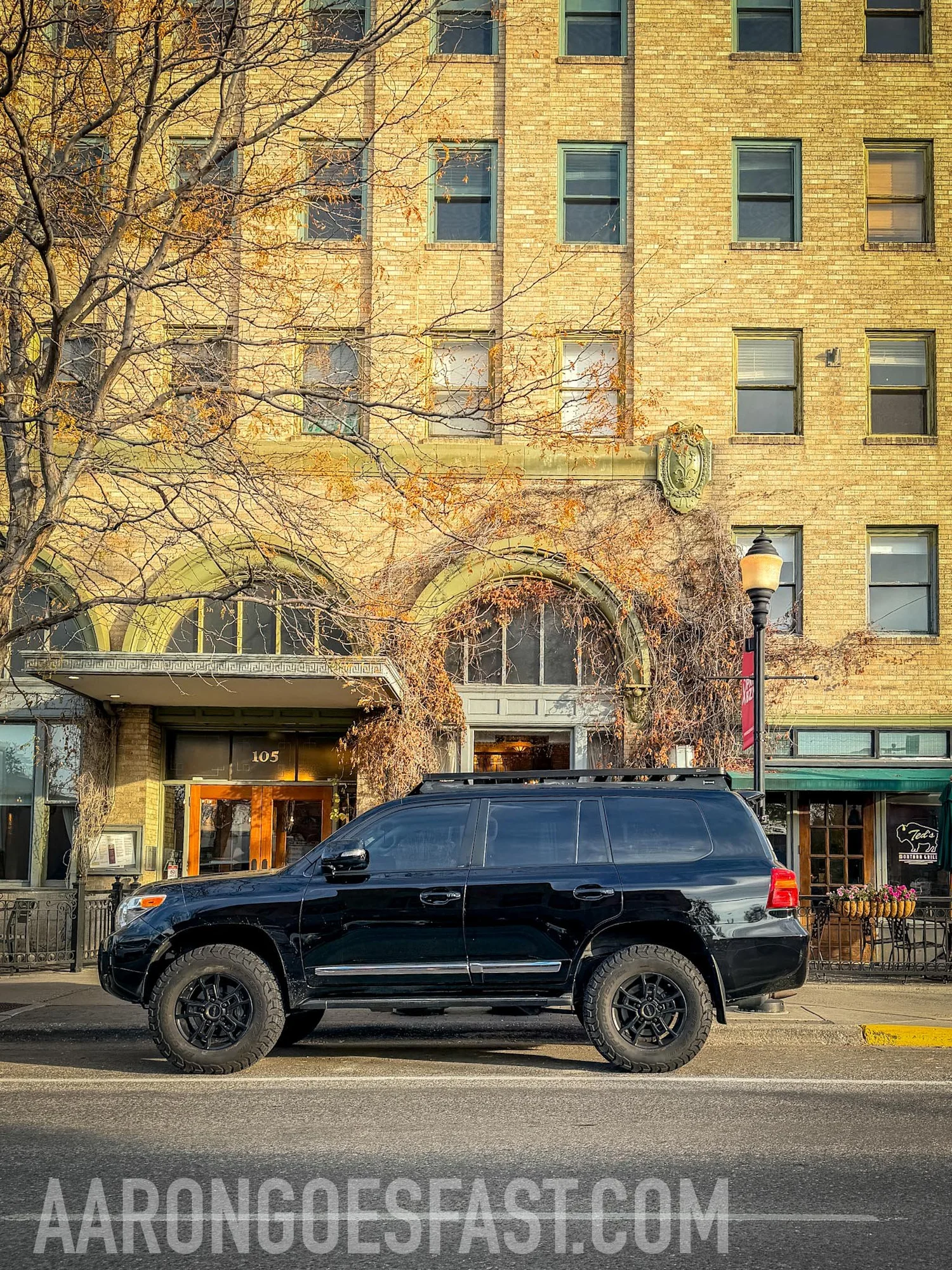 Black Toyota Land Cruiser 200 Series on black wheels parked on Main Street in downtown Bozeman, Montana