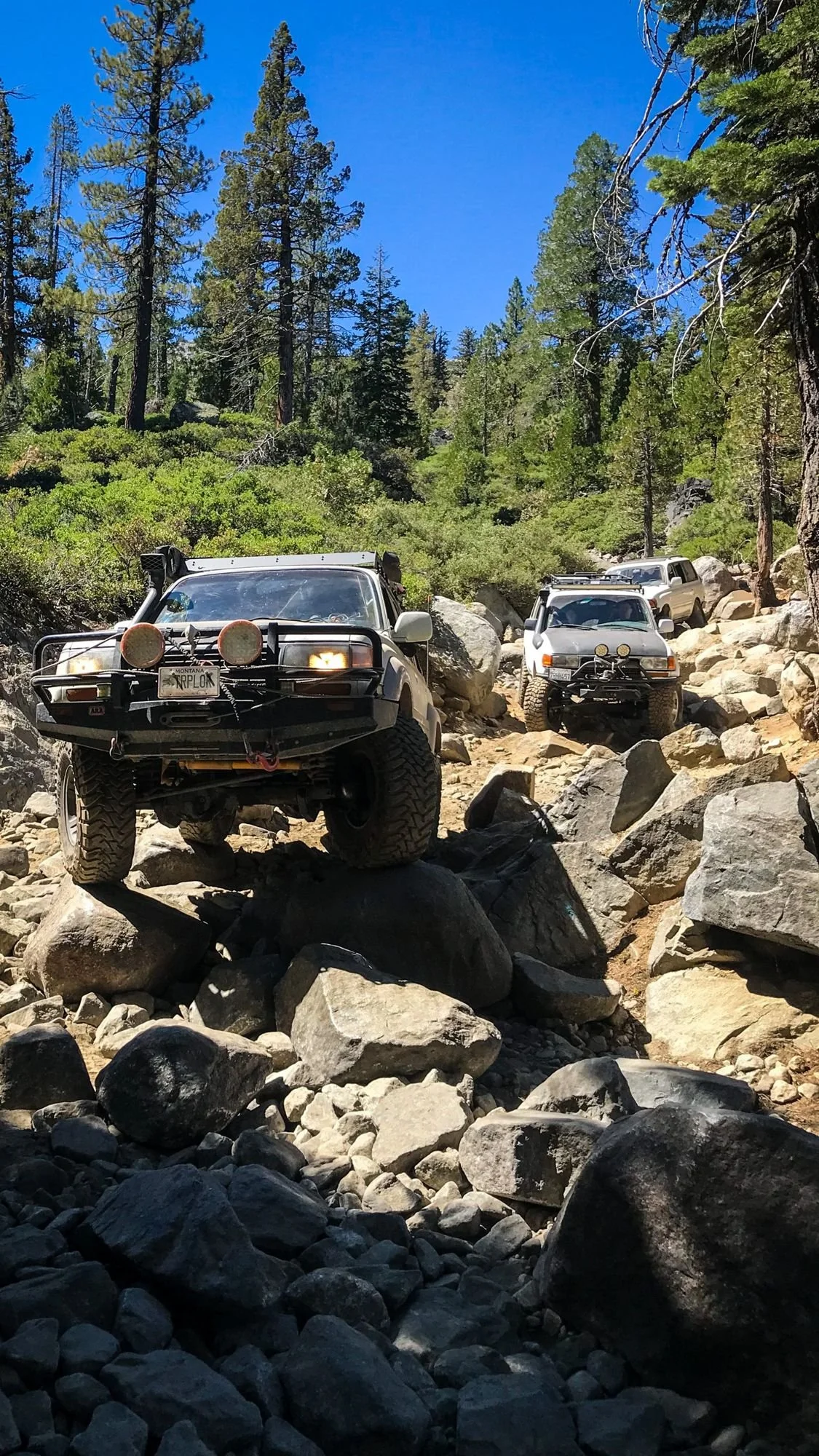 Land Cruiser with a bull bar climbing a pile of granite boulders with another truck behind on the Rubicon Trail in California during Rubithon 2022