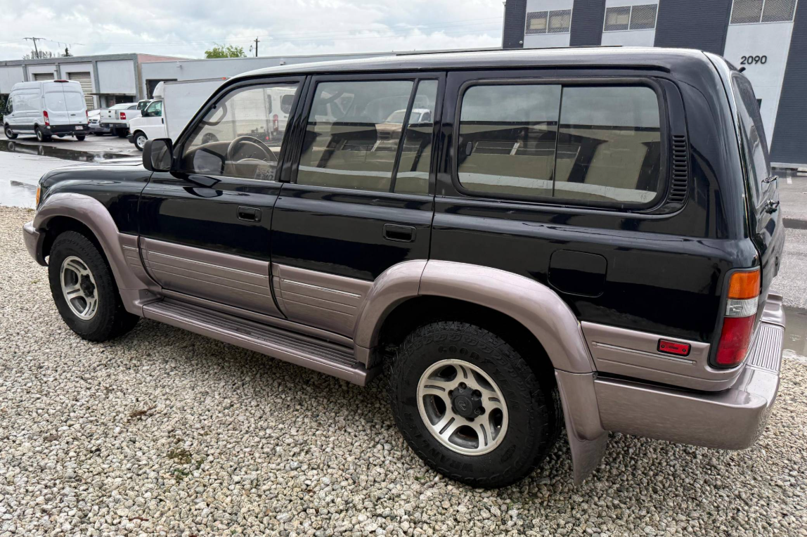 Rear three-quarter view of a black 1997 Lexus LX450 on gravel