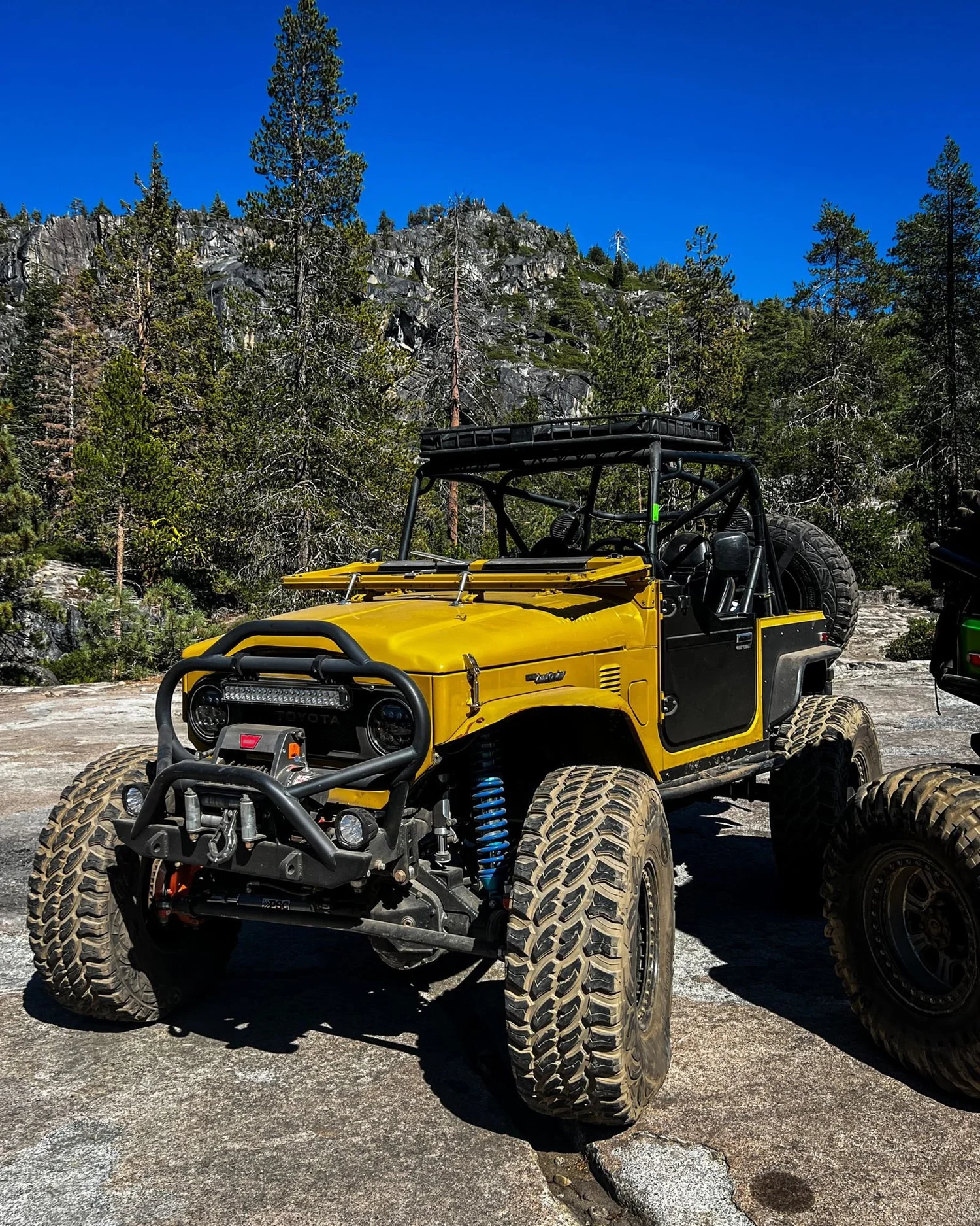 Yellow caged Toyota FJ40 Land Cruiser on granite in the sun on the Rubicon Trail in California during Rubithon 2022